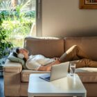 Woman relaxing on sofa with headphones during online hypnotherapy session.