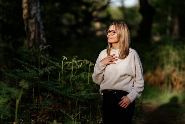 Woman in the forest holding her hand on her heart, thinking about peace this Christmas