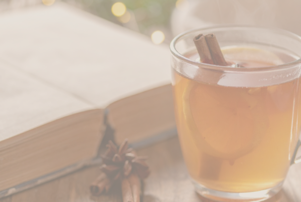 Warm winter tea with cinnamon and orange beside an open book – symbol of calm, balance, and relaxation before the festive season. Used as cover for holiday stress hypnotherapy blog.